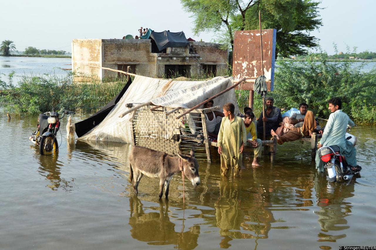 People are seen outside their flooded house, following rains and floods during the monsoon season in Suhbatpur