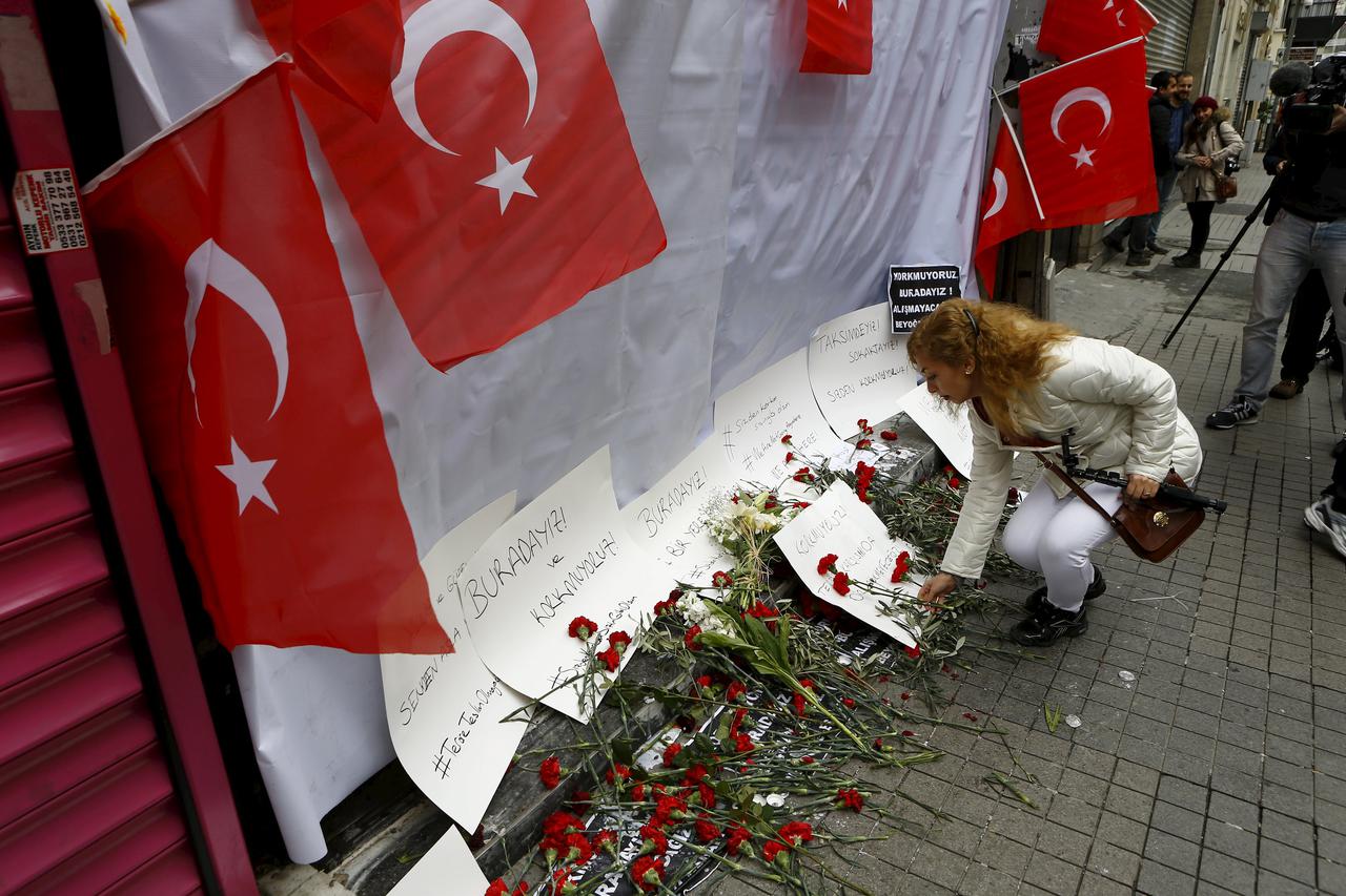 A woman places carnations at the scene of a suicide bombing at Istiklal street, a major shopping and tourist district, in central Istanbul, Turkey March 20, 2016. REUTERS/Osman Orsal