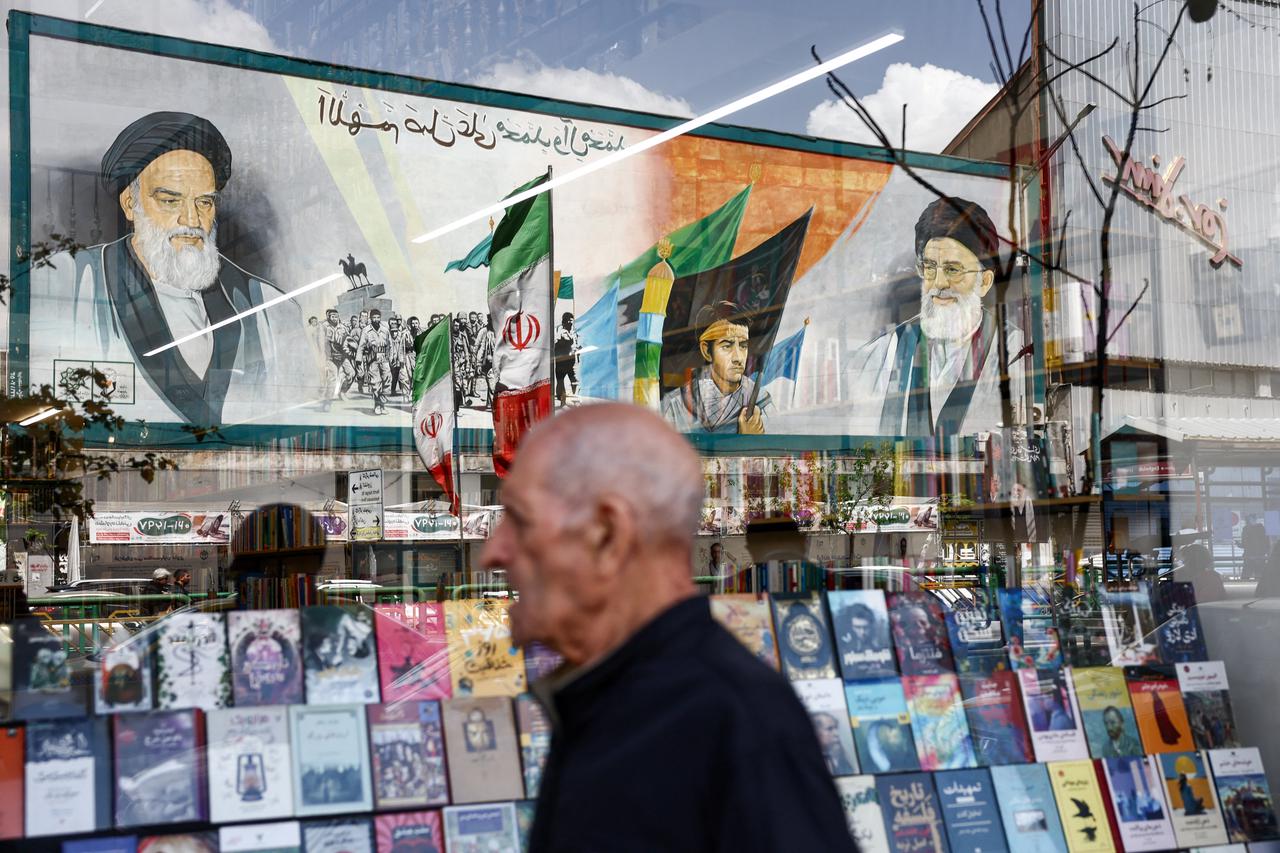 A mural depicting Ayatollah Ruhollah Khomeini and Ayatollah Ali Khamenei is reflected in a bookshop window display in Tehran