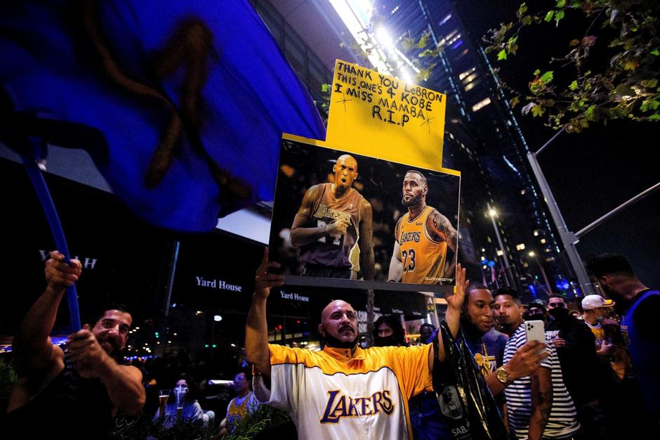 A Los Angeles Lakers fan holds a Kobe Bryant and LeBron James photo while watching on a TV at an outdoor restaurant during the 2020 NBA Final between Los Angeles Lakers and Miami Heat amid the coronavirus disease (COVID-19) outbreak, in Los Angeles