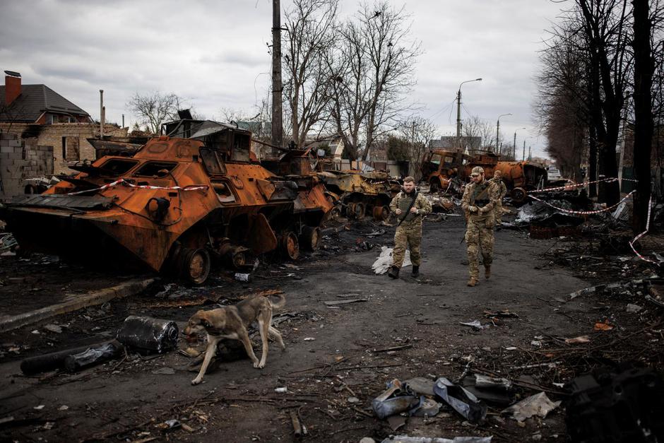 Ukrainian soldiers walk next to destroyed Russian tanks and armoured vehicles in Bucha