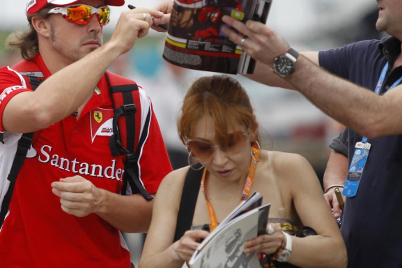 'Ferrari Formula One driver Fernando Alonso of Spain (L) signs autographs as he arrives for the third practice of the Malaysian F1 Grand Prix at the Sepang circuit outside Kuala Lumpur April 9, 2011. 