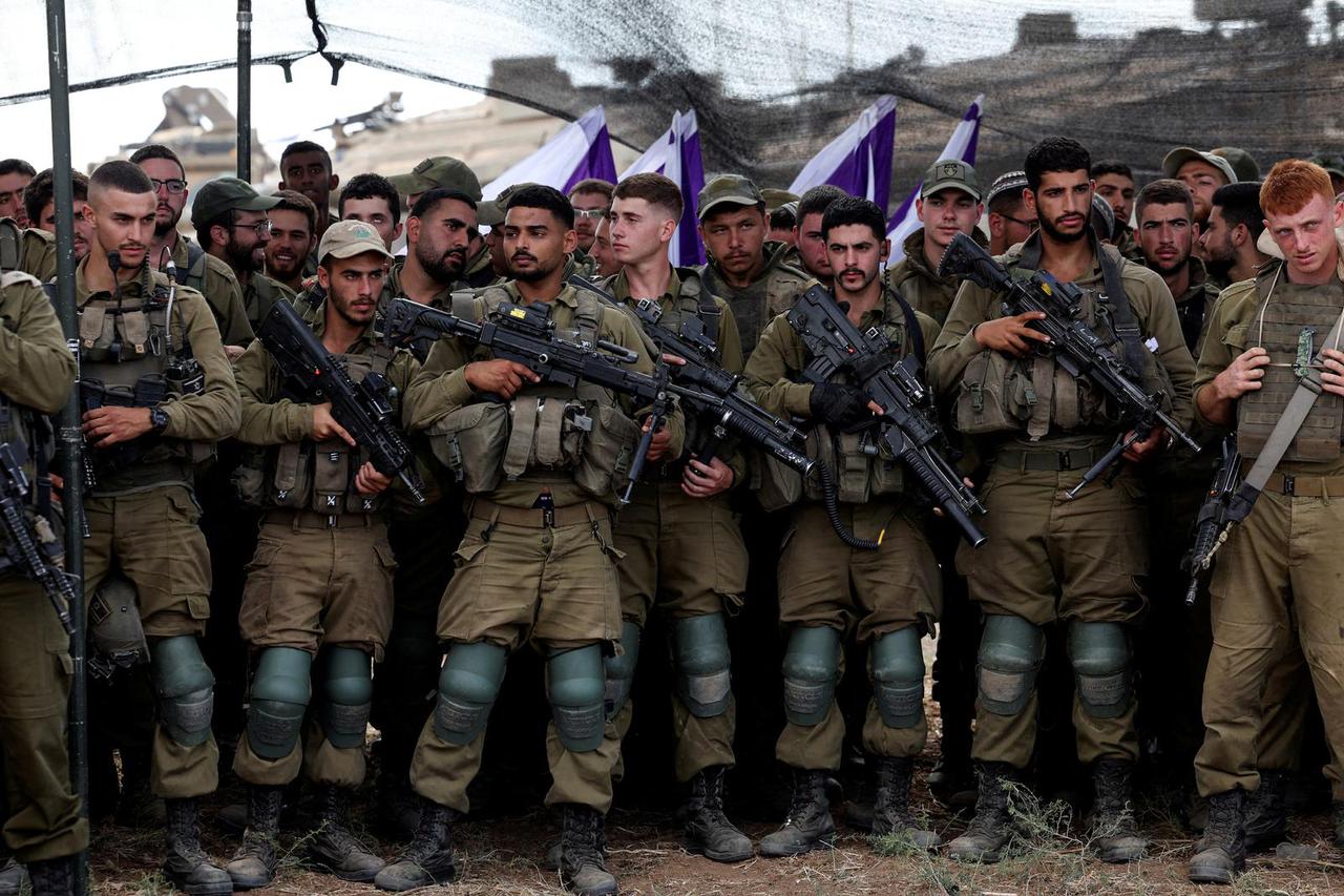 Israeli soldiers listen to Israel's Defence Minister Yoav Gallant as he meets them in a field near Israel's border with the Gaza Strip, in southern Israel
