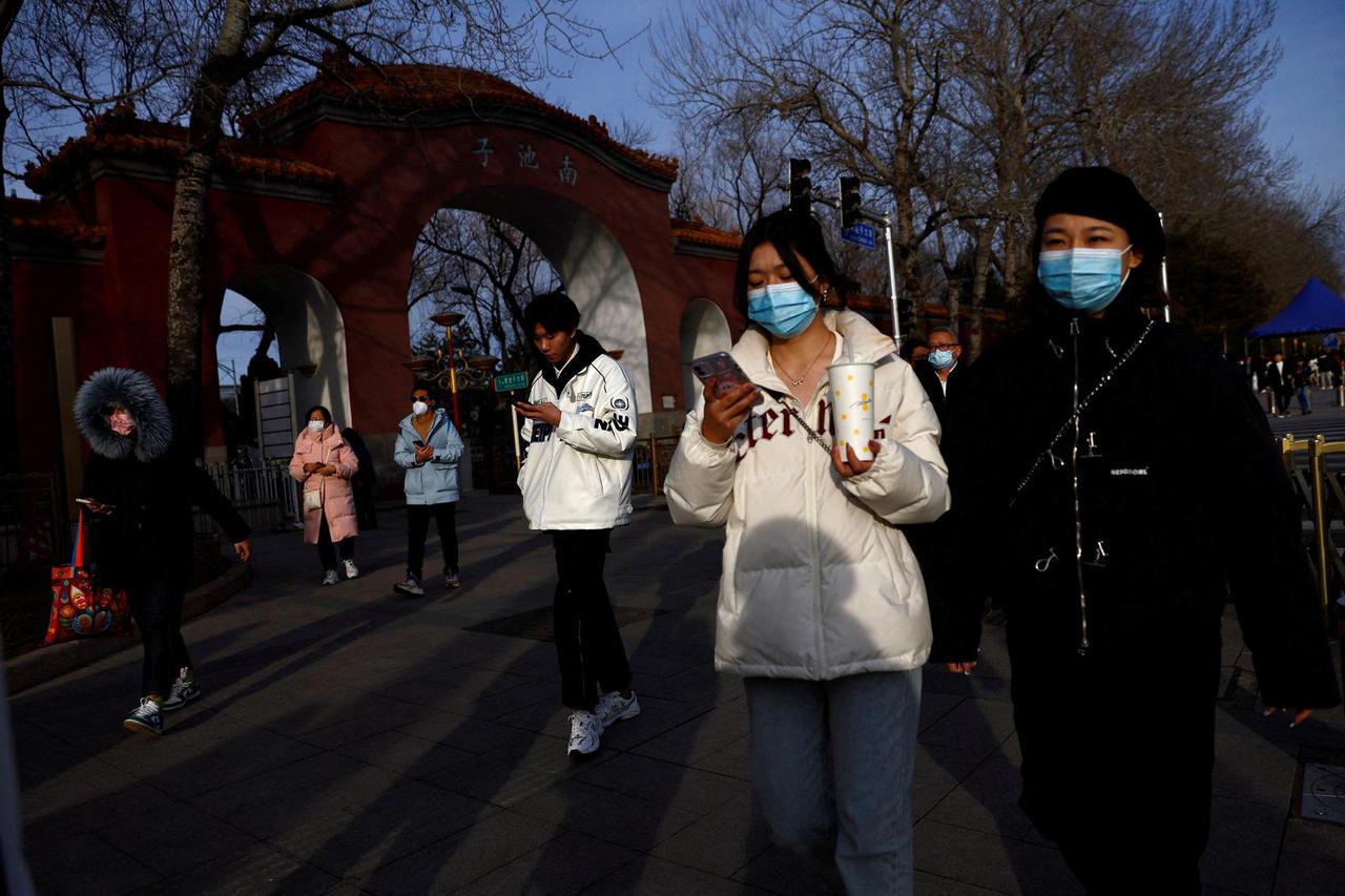 FILE PHOTO: People wearing masks walk on street in Beijing
