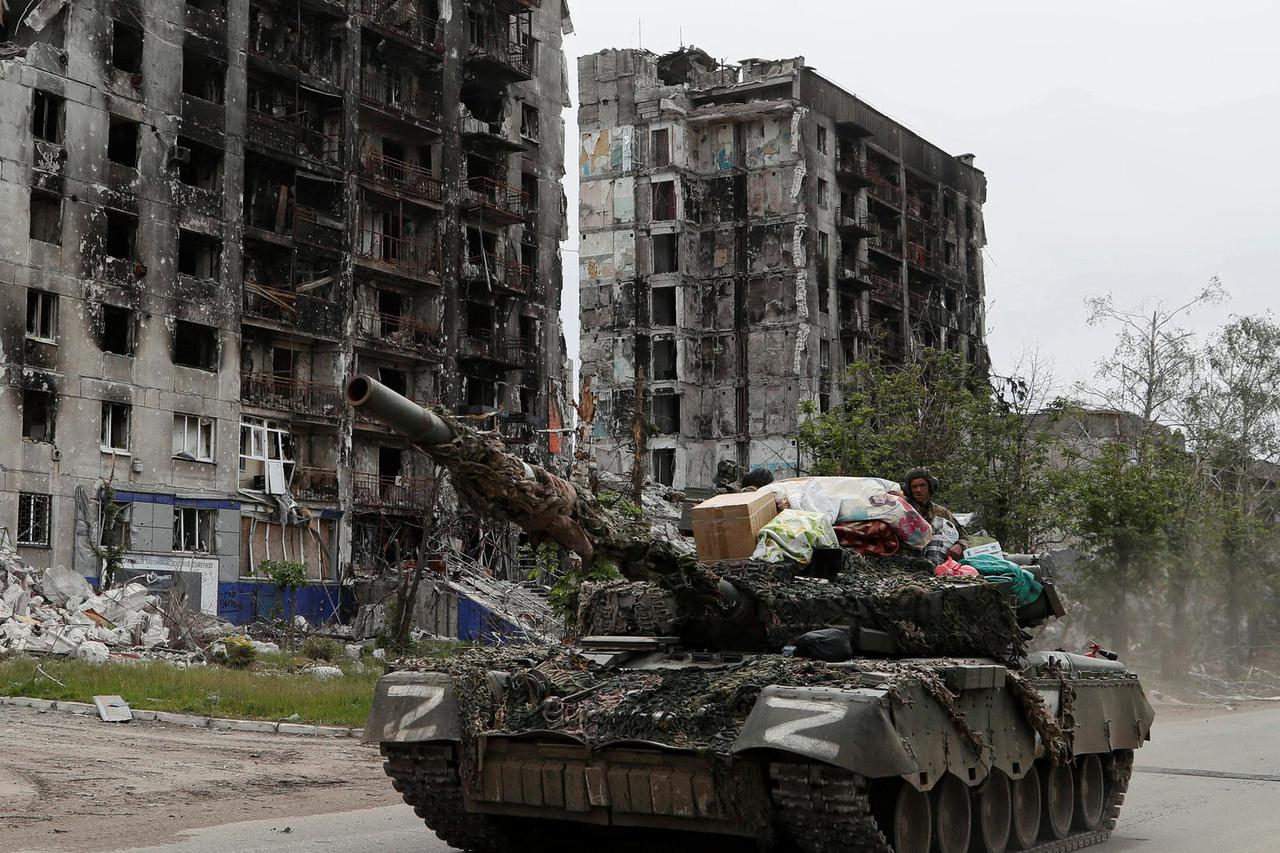 Service members of pro-Russian troops drive a tank along a street in Popasna