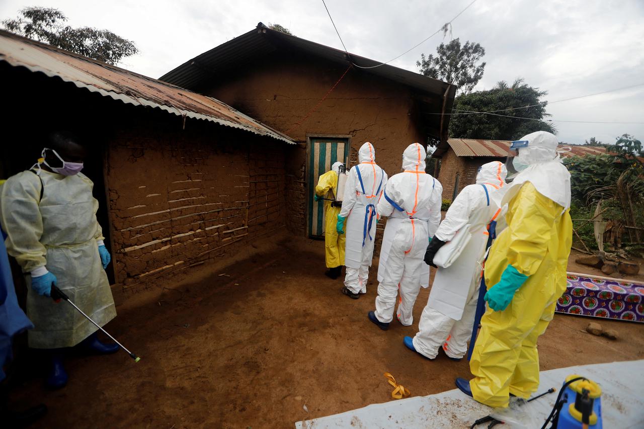 FILE PHOTO: Kavota Mugisha Robert (L), a healthcare worker who volunteered in the Ebola response, stands with decontamination gear as his colleague prepare to enter a house where a woman, 85, is suspected of dying of Ebola in the Eastern Congolese town of