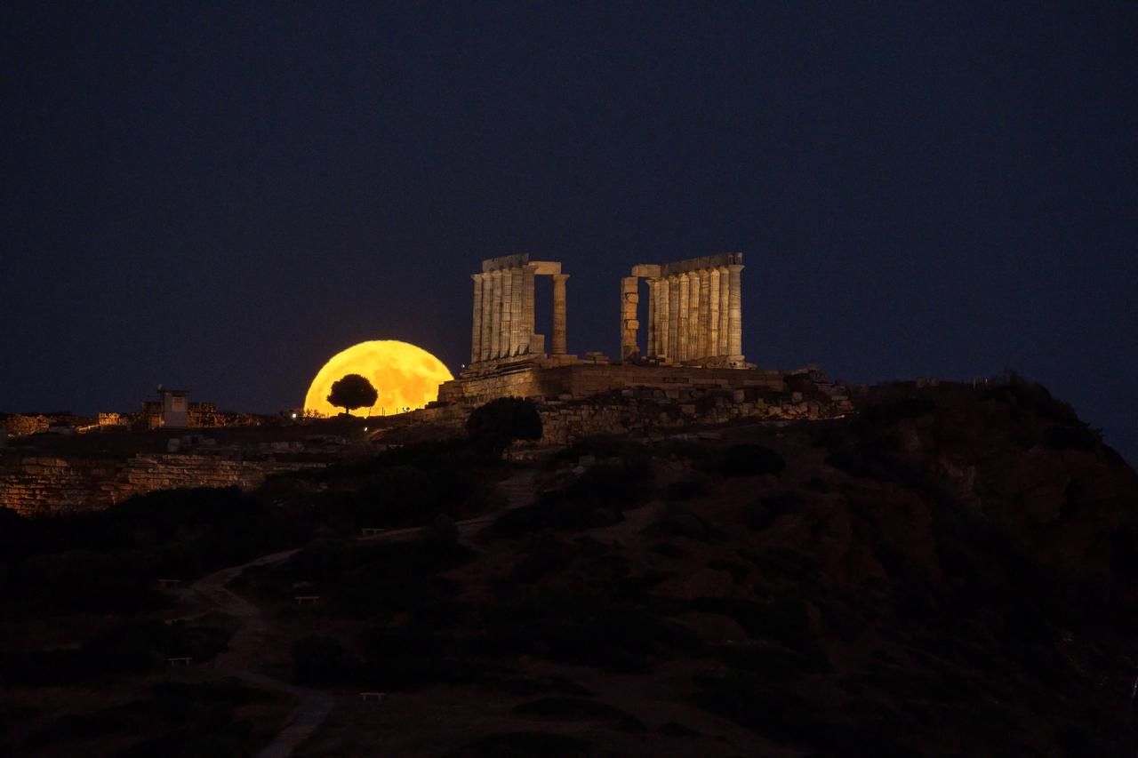 Buck full moon rises over the Poseidon Temple in Sounion, Greece