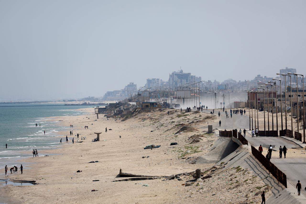 Palestinians stand, as a U.S.-built pier is pictured in the background, as seen from central Gaza Strip