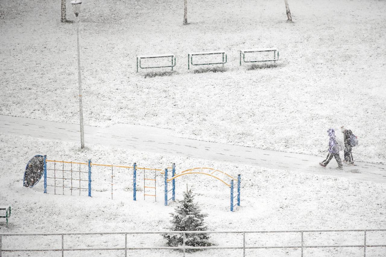 Children walk along a snow-covered pavement after snowfall  in Rzeszow