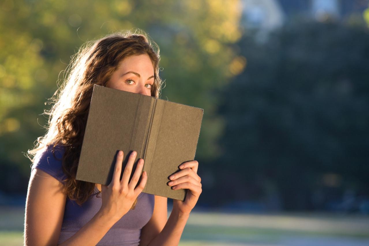 'Woman posing with book outdoors'