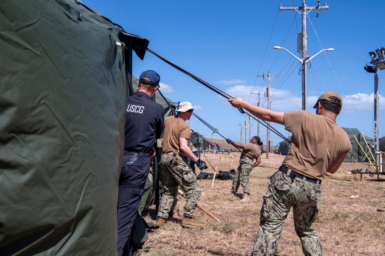 U.S. Navy sailors and Coast Guardsmen erect expeditionary shelter tents at Naval Station Guantanamo Bay
