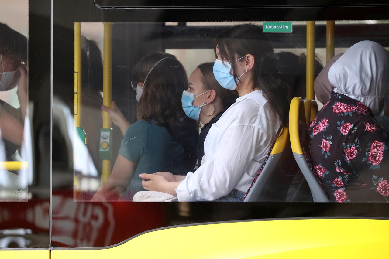 People wear face masks as they use a public transport bus in Berlin