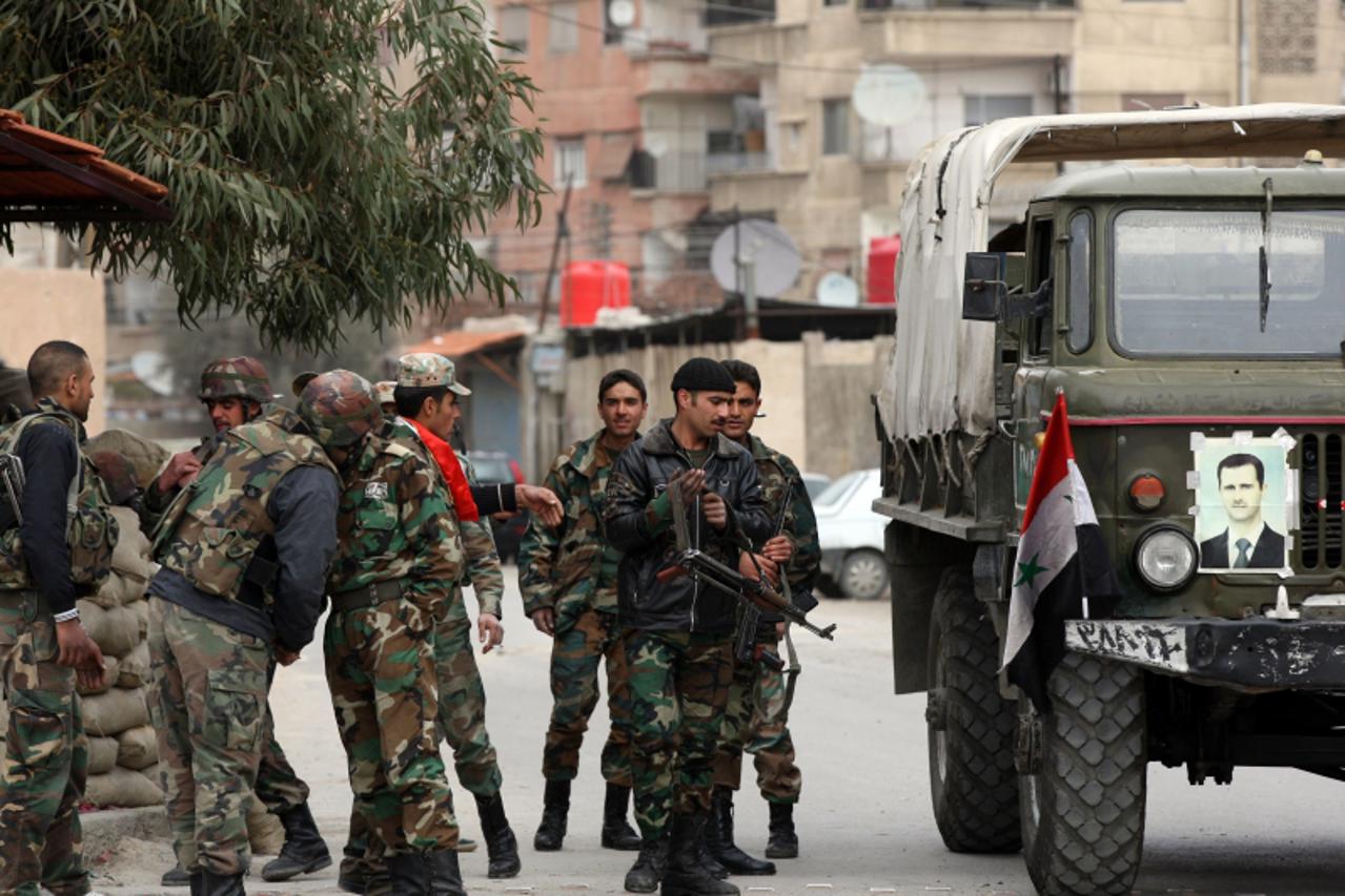 'Syrian army soldiers stand at a checkpoint in the city of Harasta, 9 km north of Damascus on February 15, 2012. Syria\'s President Bashar Al-Assad has called a referendum on a new constitution that w