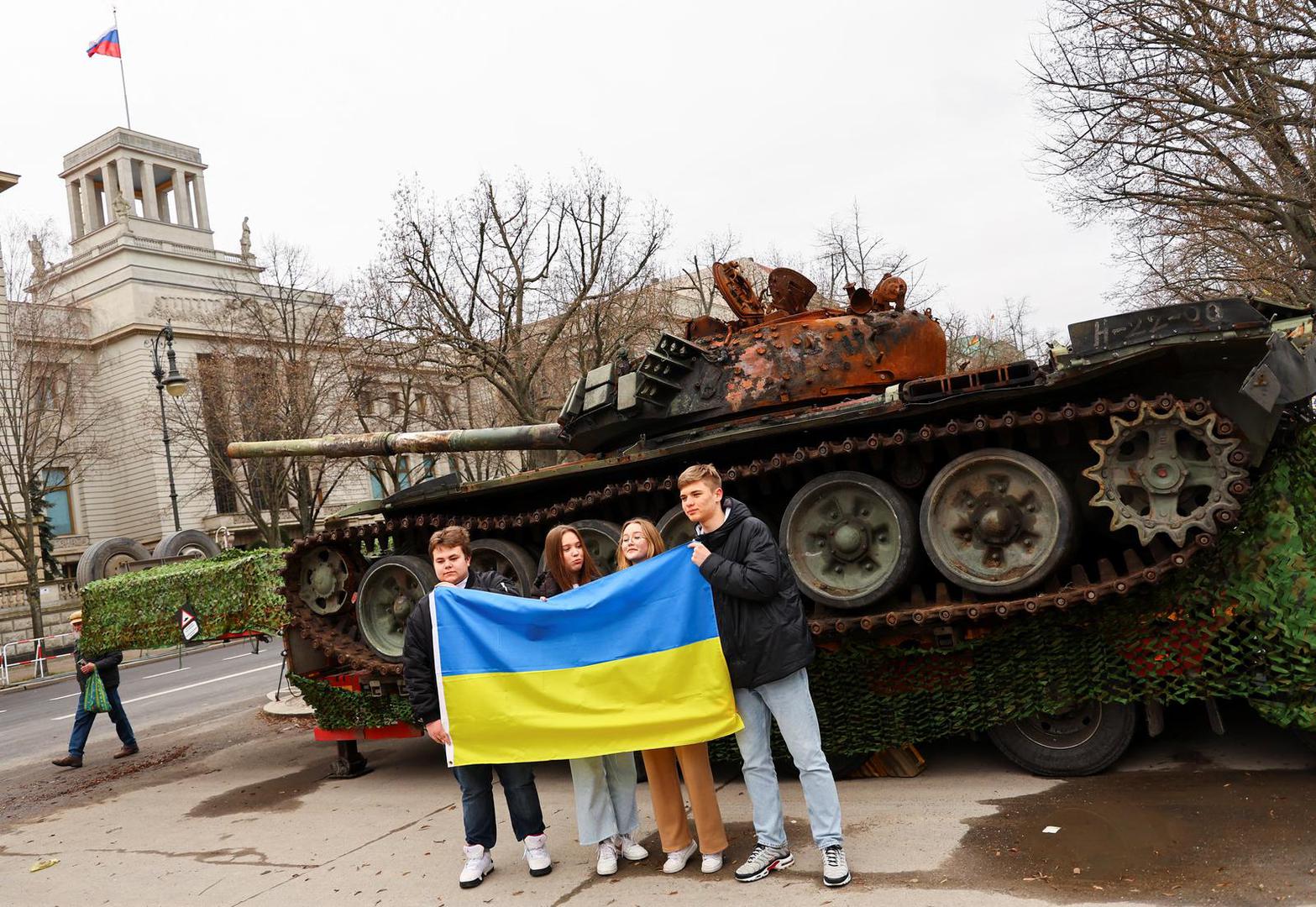 Ukrainian refugees Vladyslav Morozov from Dnipro, Dariia Harbar and Maryana Yartseva from Kyiv and Daniel Chumachenko from Kharkiv hold the Ukrainian national flag in front of the remains of a destroyed Russian T-72 tank, secured from the Ukrainian village of Dmytrivka, outside Kyiv, kept on display near the Russian embassy at Unter den Linden boulevard, during an event to mark the one-year anniversary of the Russian invasion of Ukraine, in Berlin, Germany, February 24, 2023. REUTERS/Fabrizio Bensch Photo: Fabrizio Bensch/REUTERS