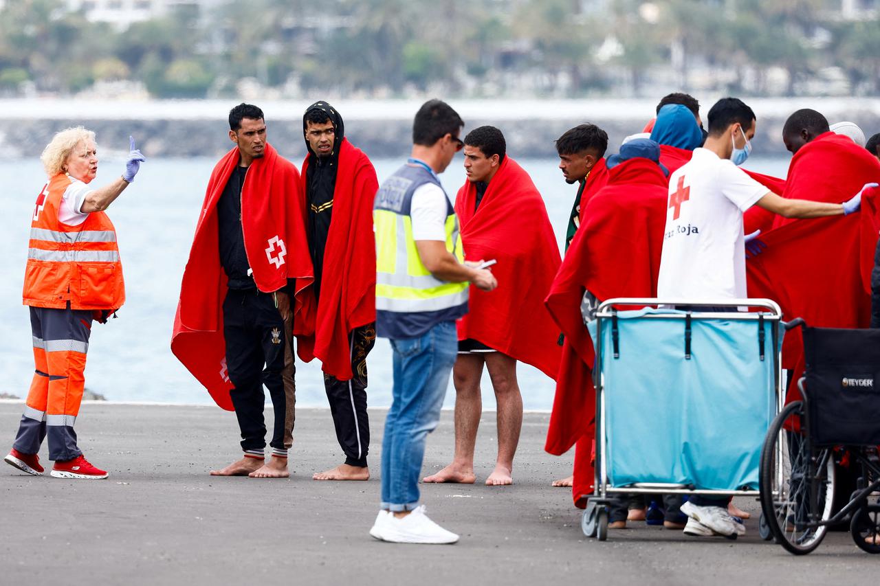 Migrants wait to be assisted by the Red Cross after disembarking from a Spanish coast guard vessel at the port of Arguineguin