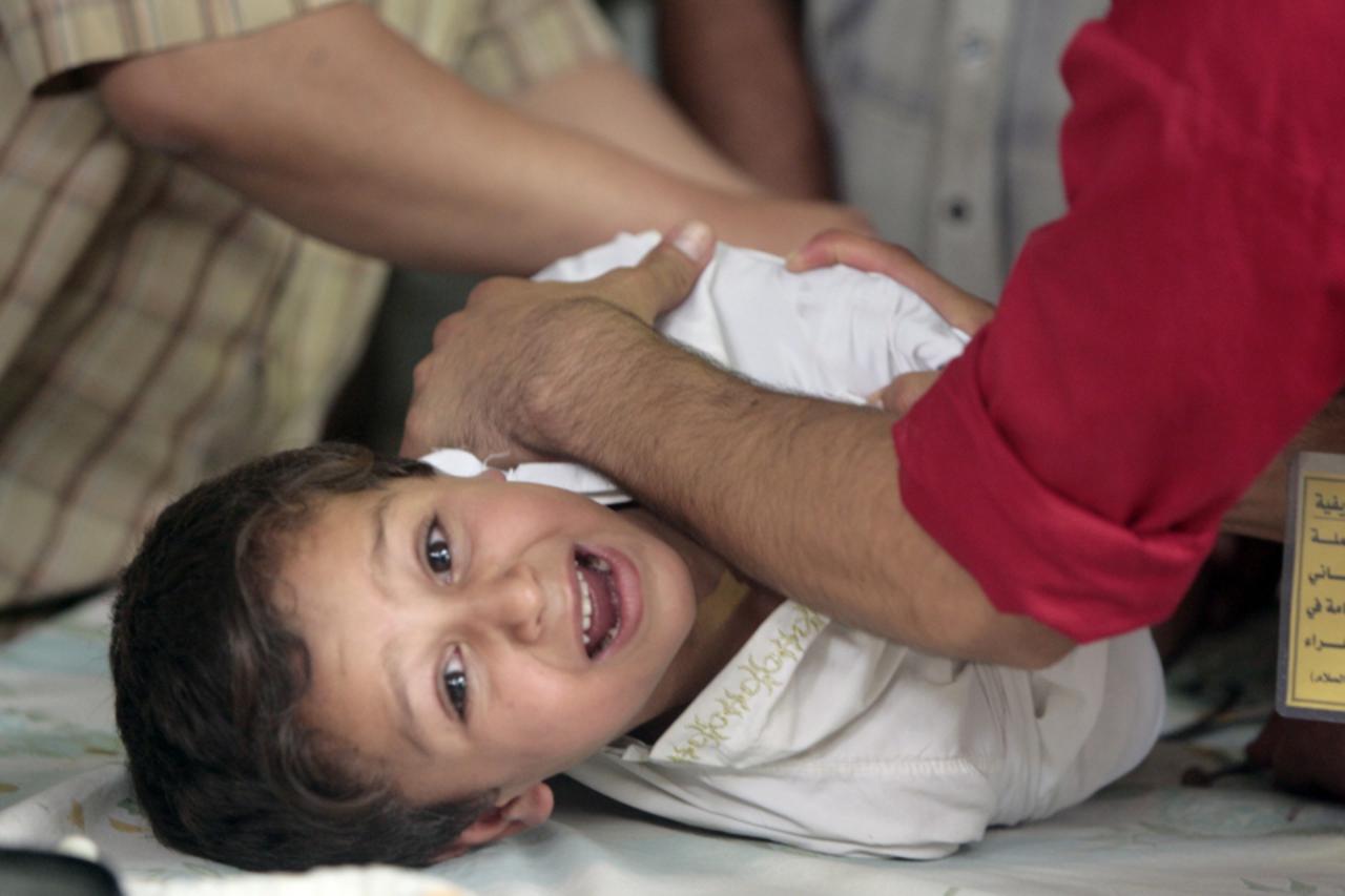 obrezivanje 'A little boy cries as he undergoes circumcision in the eastern Baghdad district of Sadr City, on July 10, 2009. Two hundred boys were circumcised for free by medics using local anesthetic