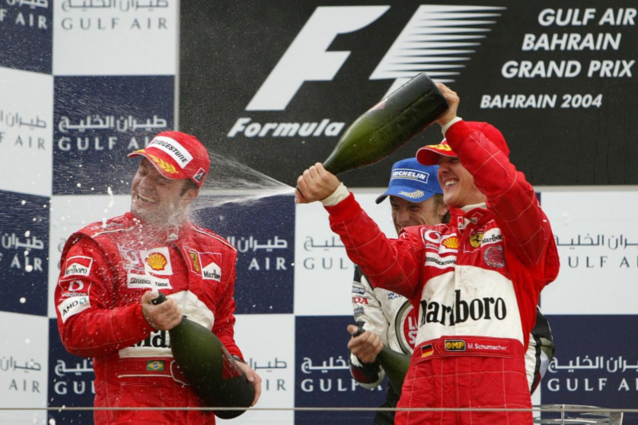 'Formula One World Champion Ferrari Michael Schumacher (R) of Germany and BAR Jenson Button of Great Britain (C) spray \'Warrd\', a fizzy fruit juice provided instead of the usual champagne, on Ferrar