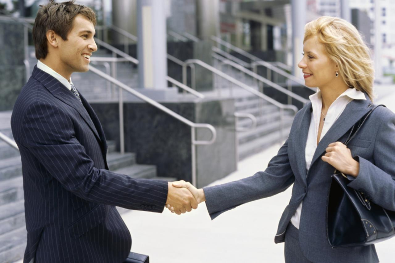 'Side profile of a businessman and a businesswoman shaking hands'