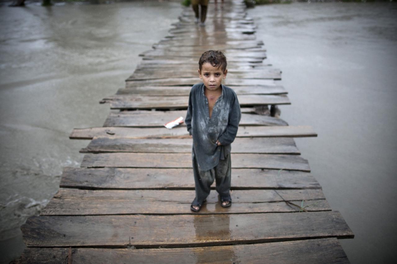 'A flodod-affected Pakistani child walks on a wooden bridge towards the village of Shah Alam on the outskirts of Peshawar on August 7, 2010, after moving from his flood-affected village.  Pakistan rac