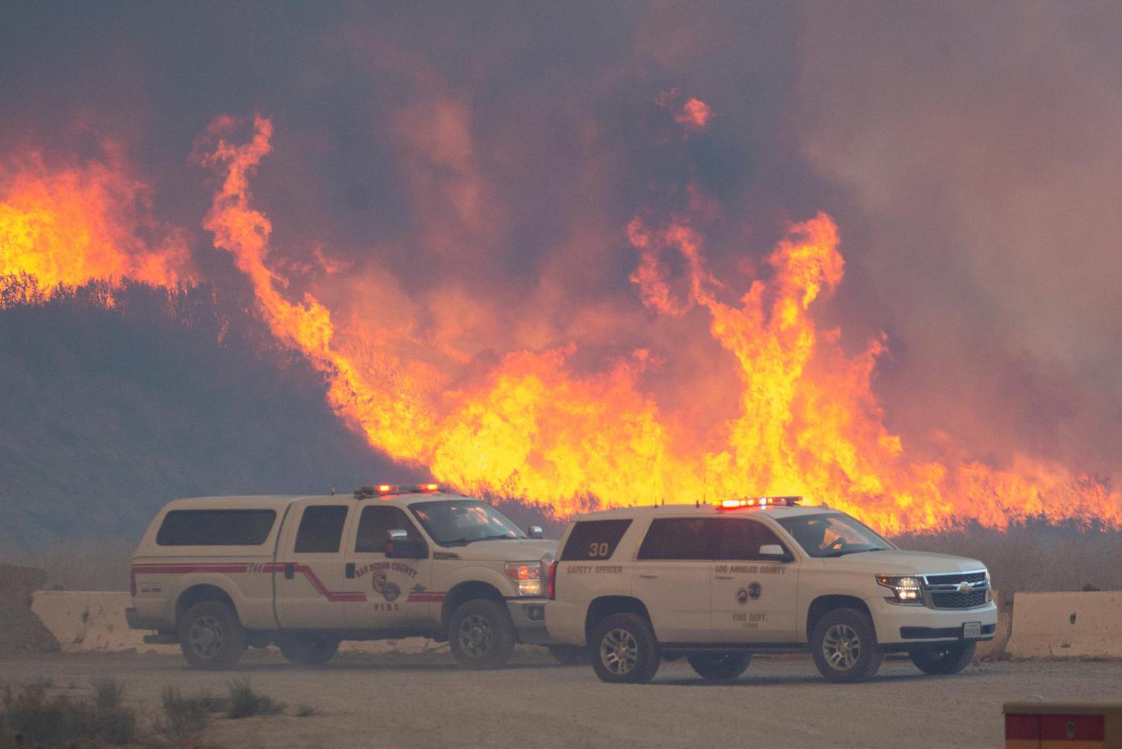 Flames rise in the background, behind emergency services vehicles, as firefighters and aircraft battle the Hughes Fire near Castaic Lake, north of Santa Clarita, California, U.S. January 22, 2025. REUTERS/Ringo Chiu Photo: RINGO CHIU/REUTERS