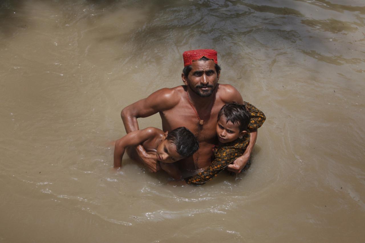 'A man wades through flood waters towards a naval boat while evacuating his children in Sukkur, located in Pakistan\'s Sindh province August 8, 2010. Pakistani navy boats sped across miles of flood wa