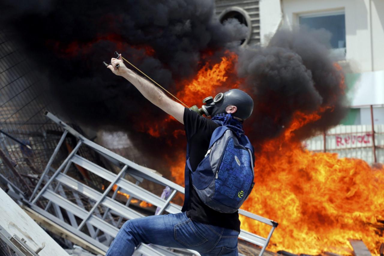 'A protester uses a slingshot to throw stones at riot police during a protest at Taksim Square in Istanbul June 11, 2013. Turkish riot police fired tear gas and water cannon at hundreds of protesters 