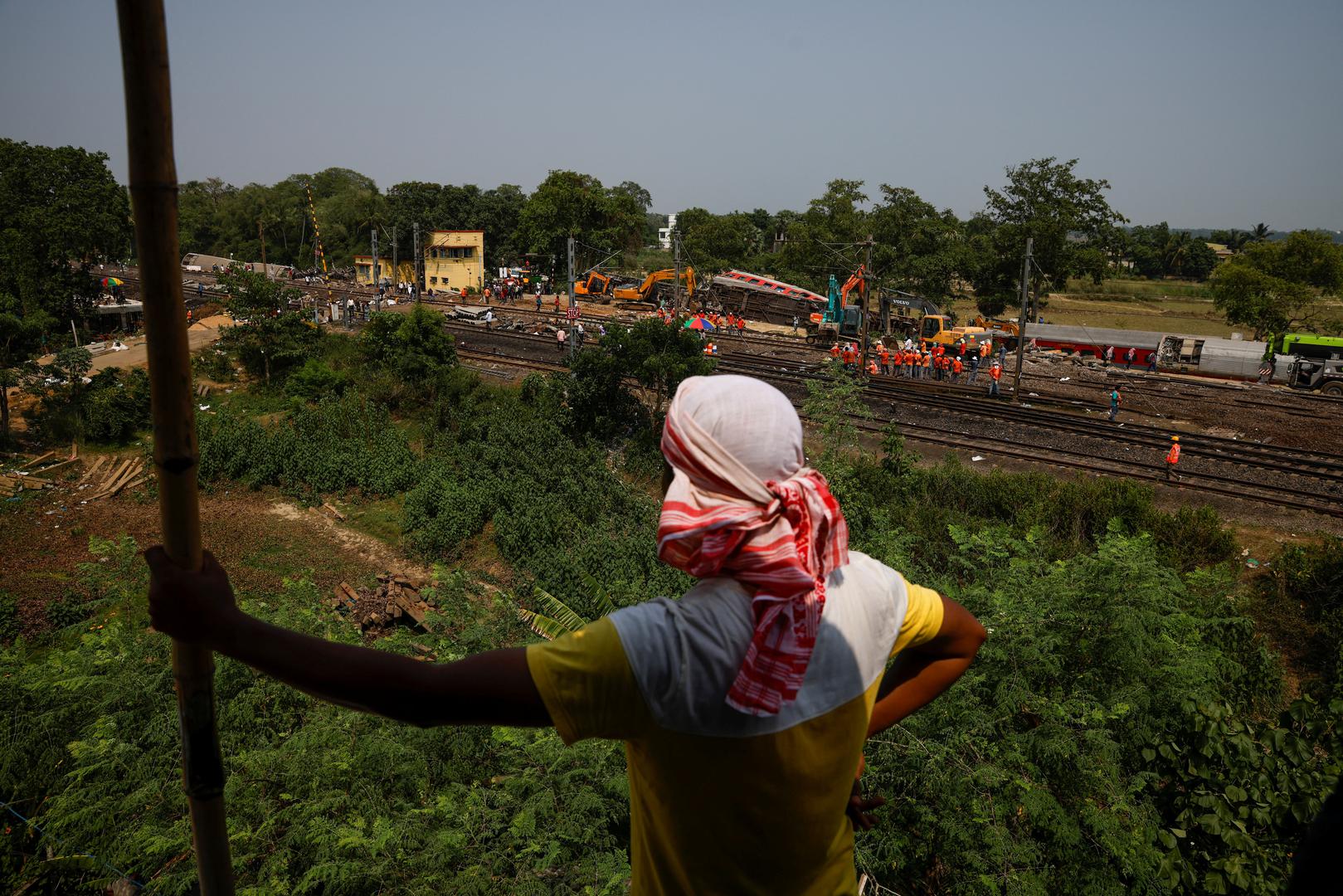 A man stands on the roof of a house as he watches heavy machinery removing damaged coaches from the railway tracks at the site of a train collision following the accident in Balasore district in the eastern state of Odisha, India, June 4, 2023. REUTERS/Adnan Abidi Photo: ADNAN ABIDI/REUTERS