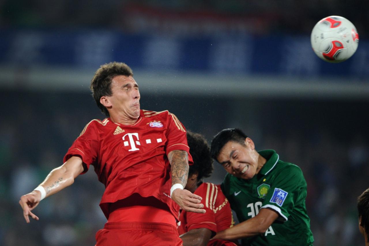'Mario Mandzukic (L) of Bayern Munich heads the ball against Beijing Guoan during a friendly match in Beijing on July 24, 2012. Bayern Munich beat Guoan 6-0. AFP PHOTO / Ed Jones'