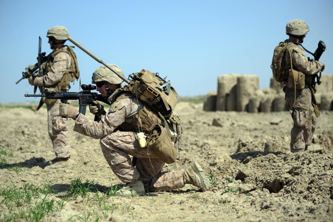 'US Marines from 2nd Battalion, 1st Marines Regiment keep watch as others check for improvised explosive devices (IEDs) during a patrol in Garmser, Helmand Province, Afghanistan on March 7, 2011. Ther