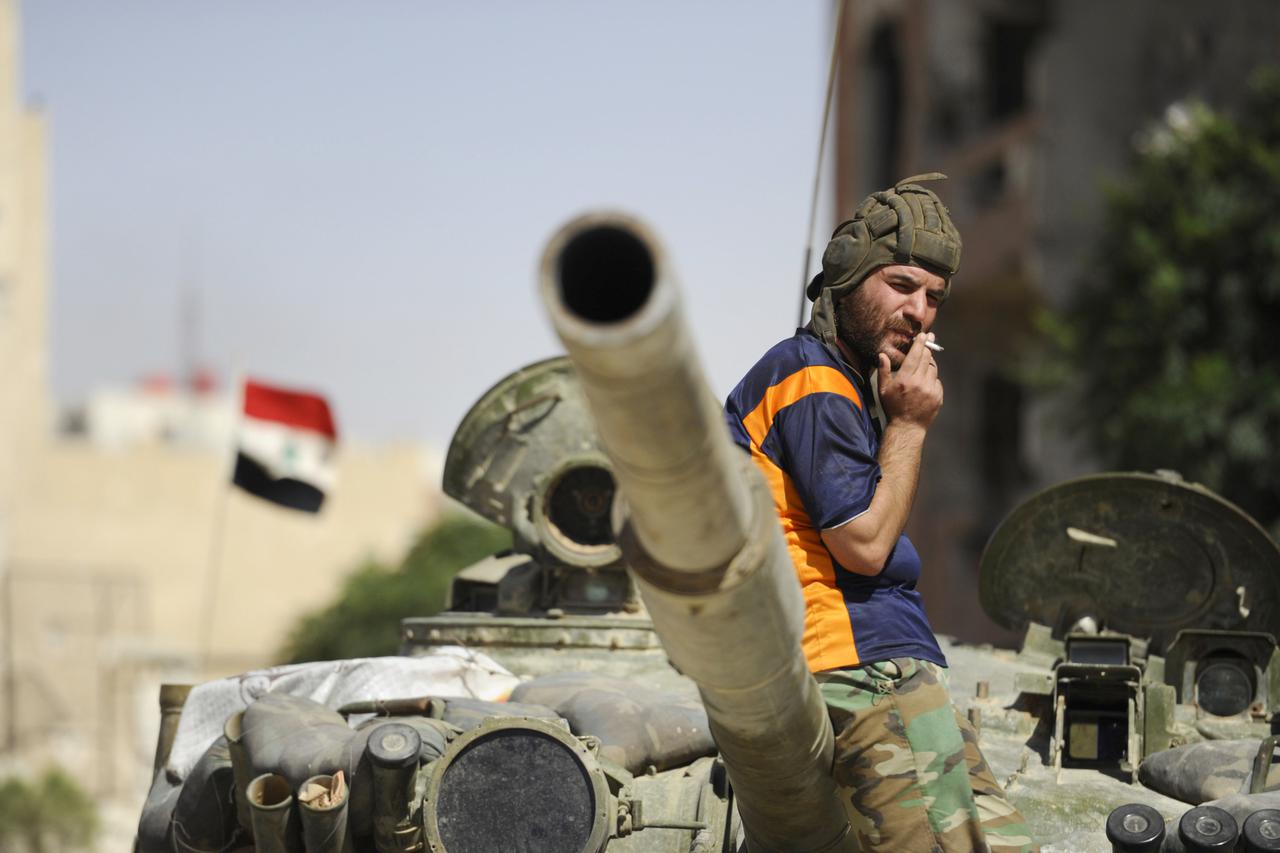 A soldier loyal to Syria's President Bashar Al-Assad smokes while resting on a tank in Adra al-Omalia, after taking control of the area from rebel fighters September 25, 2014. Syrian government forces overran rebels in the town northeast of Damascus on Th