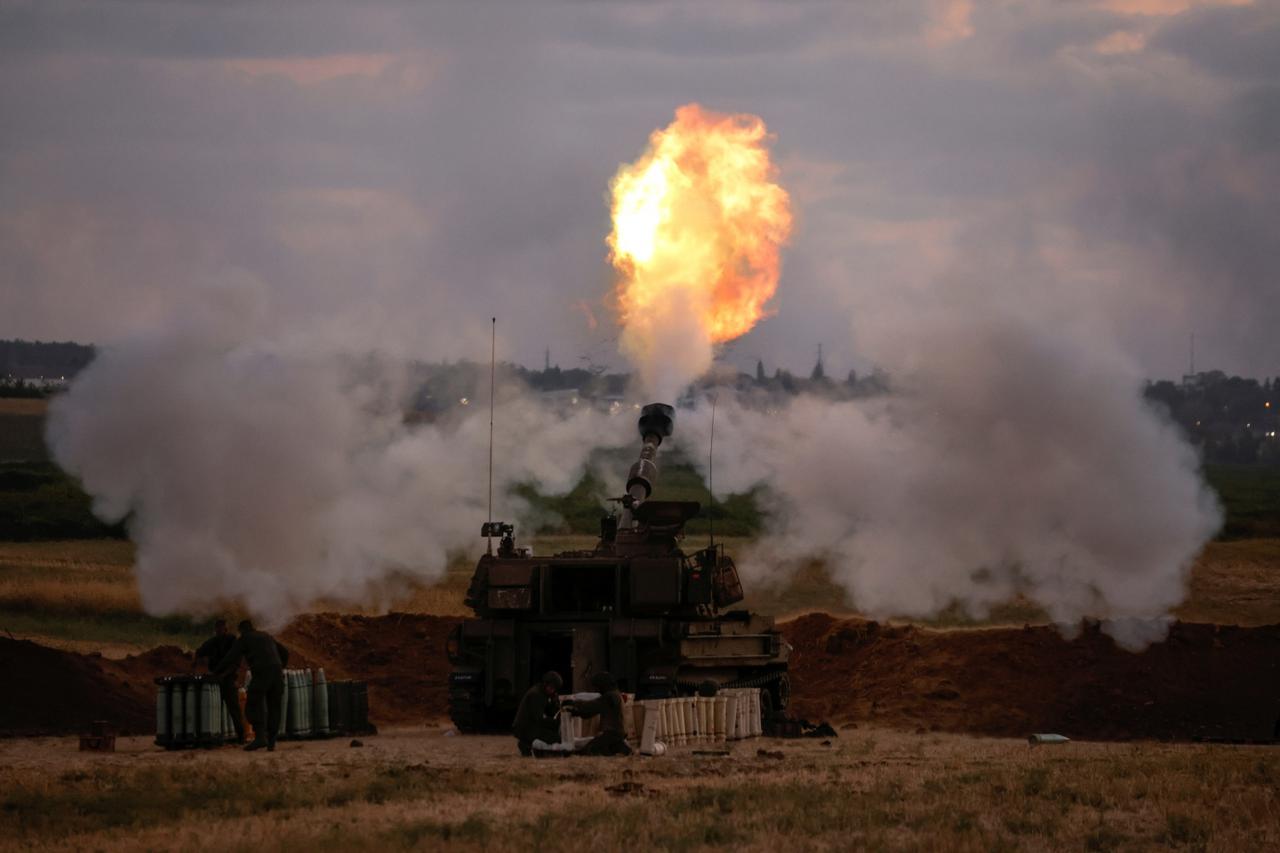 Israeli soldiers work at an artillery unit as it fires near the border between Israel and the Gaza strip, on the Israeli side