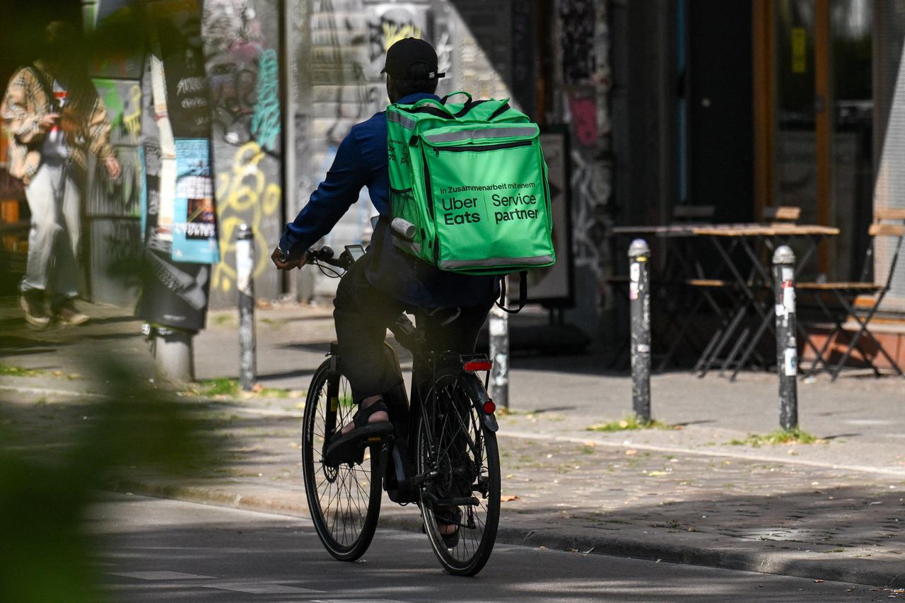 A food delivery cyclist with an Uber Eats backpack rides a bike, in Berlin