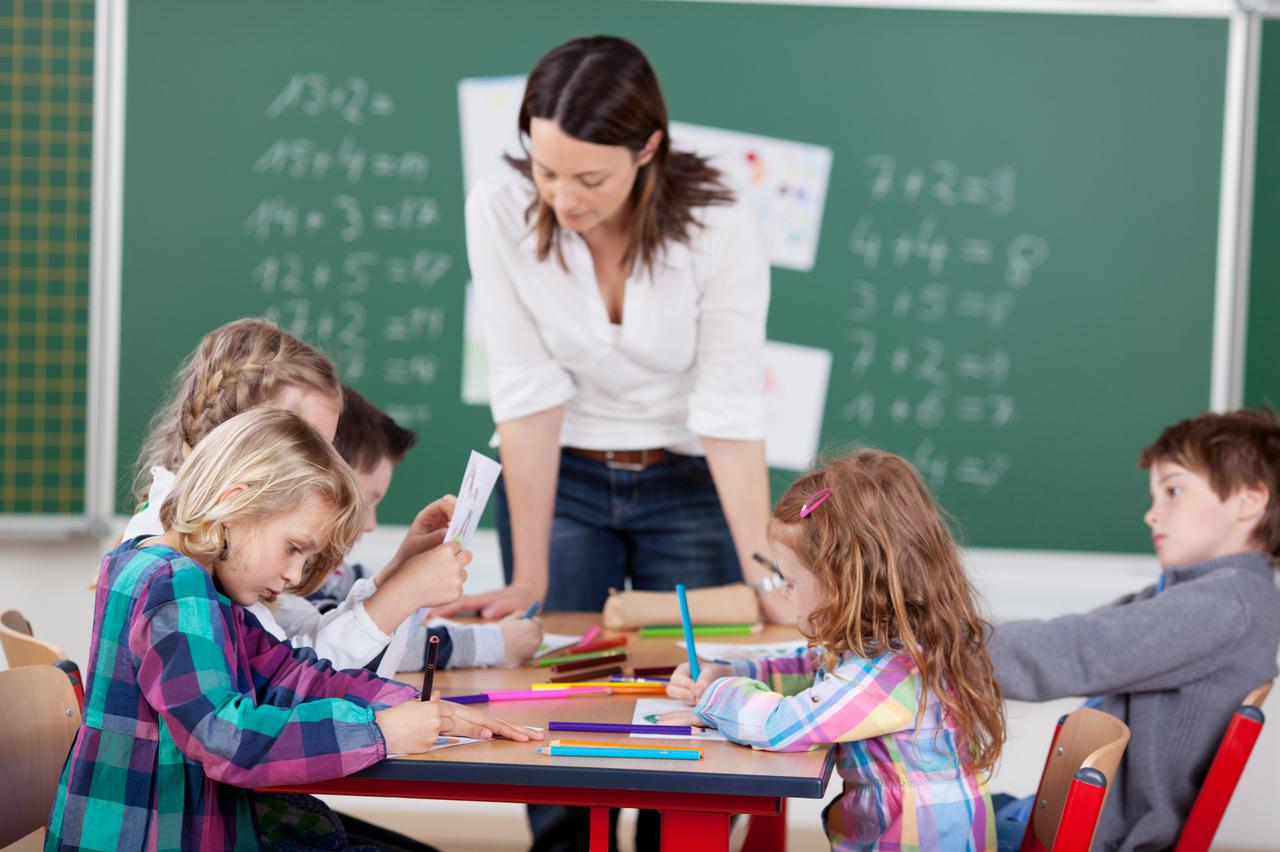 Portrait of teacher helping her busy students in art class