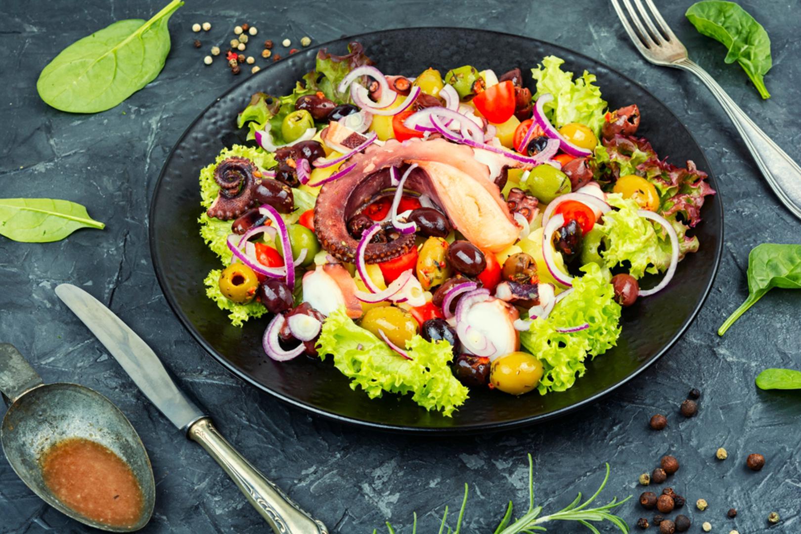 Salata od hobotnice s maslinama i krumpirom: Kuhanu hobotnicu narežite, dodajte kuhani krumpir, crvene kapule i šaku maslina. Začinitе maslinovim uljem, limunom, peršinom i s malo papra, bez previše kompliciranja. Masline daju slani kontrast i podignu sve bez dodatne soli. Ostavite 15 minuta da se prožme i poslužite kao laganu večeru ili svečanu hladnu platu.