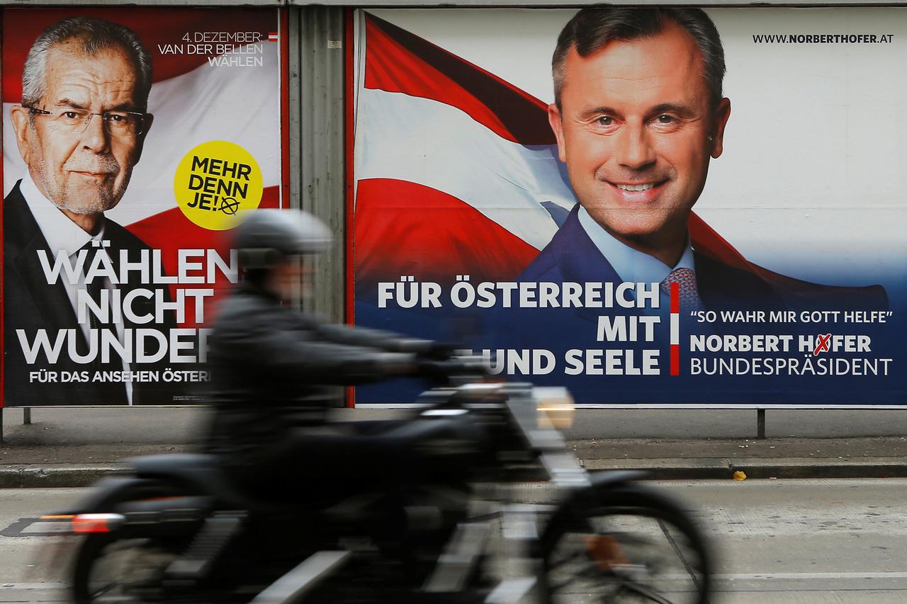 A motorcyclist passes presidential election campaign posters of Alexander Van der Bellen (L), who is supported by the Greens, reading 