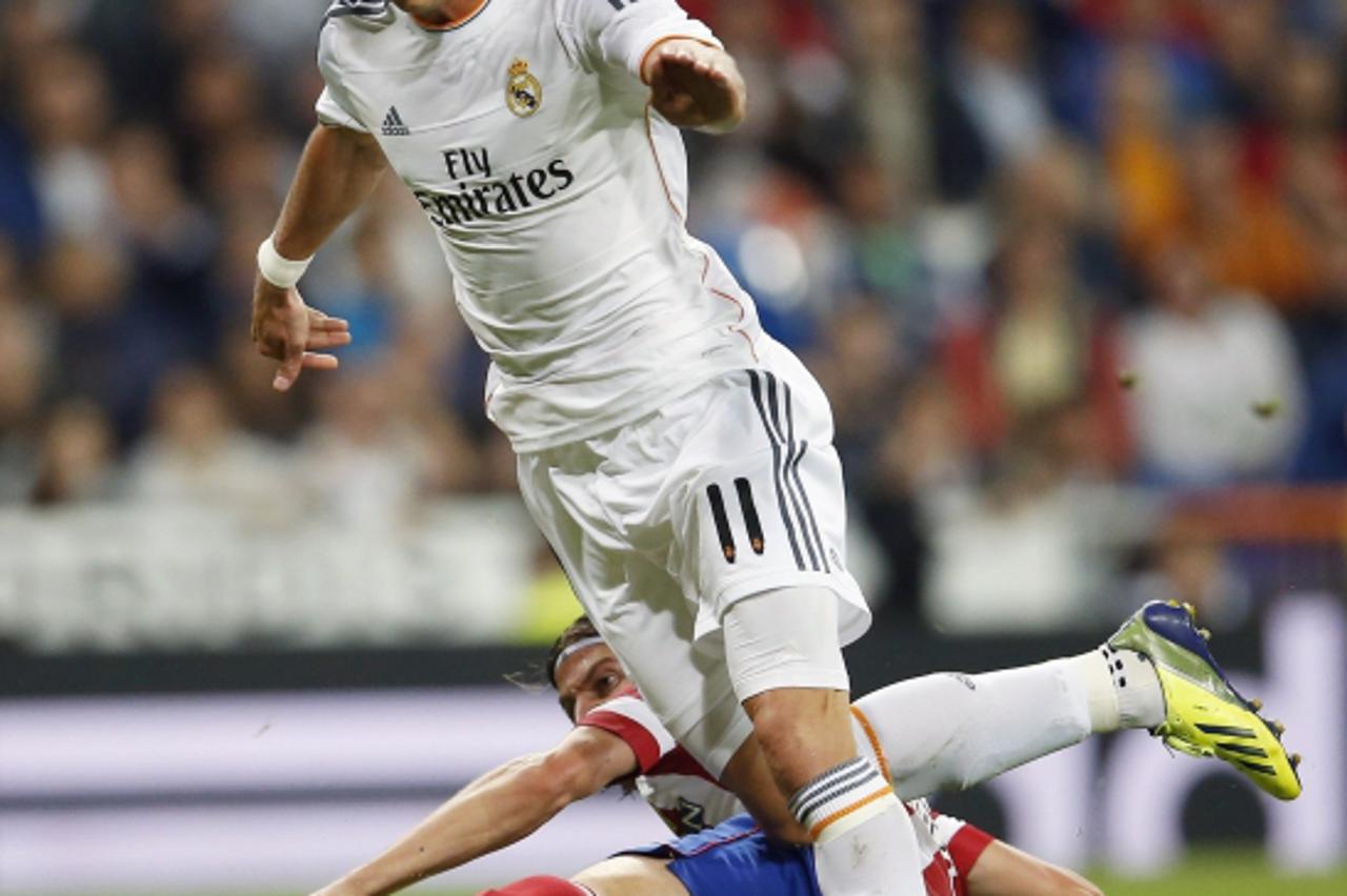 'Real Madrid\'s Gareth Bale (front) fights for the ball with Atletico Madrid\'s Filipe Luis during their Spanish first division soccer match at Santiago Bernabeu stadium in Madrid September 28, 2013. 