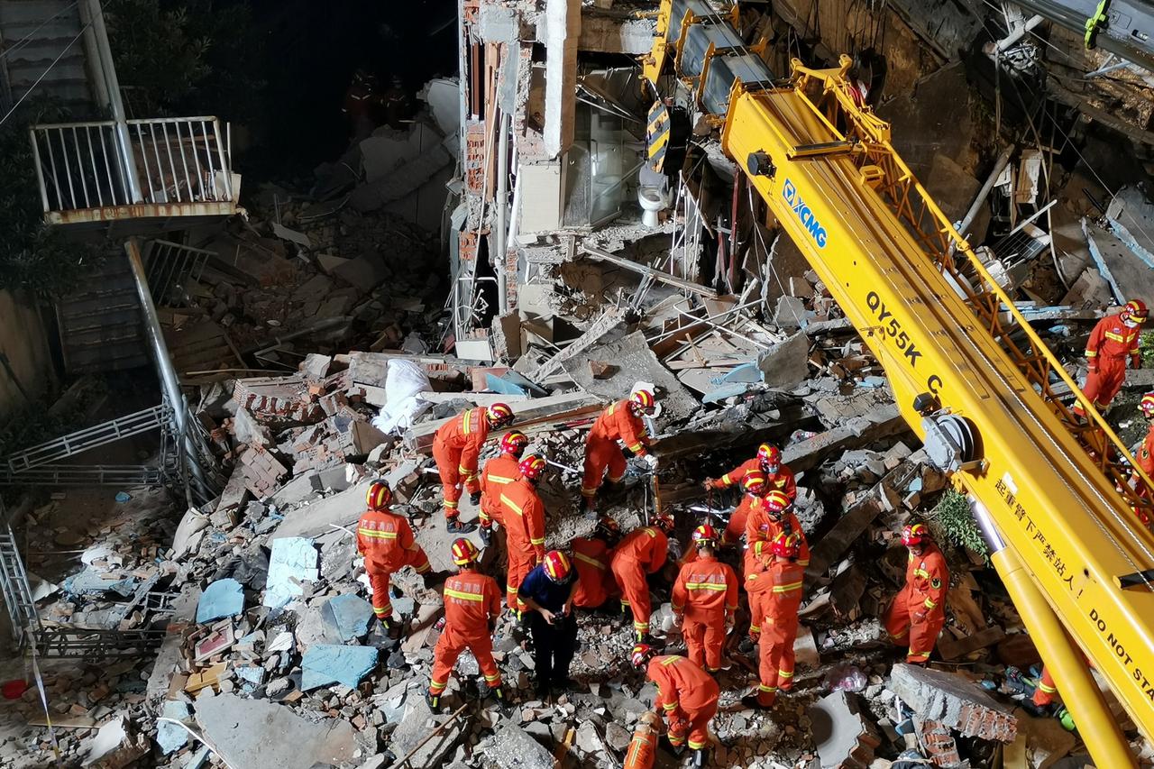 Rescue workers work next to a crane at the site where a hotel building collapsed in Suzhou