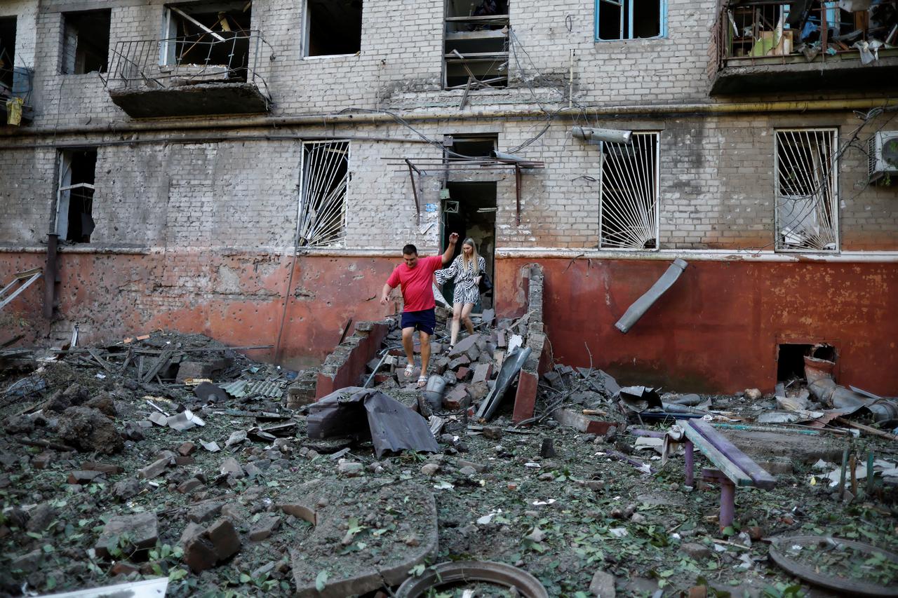 People walk after checking damages in a residential building damaged after a Russian strike, as Russia's attack in Ukraine continue, in Kramatorsk