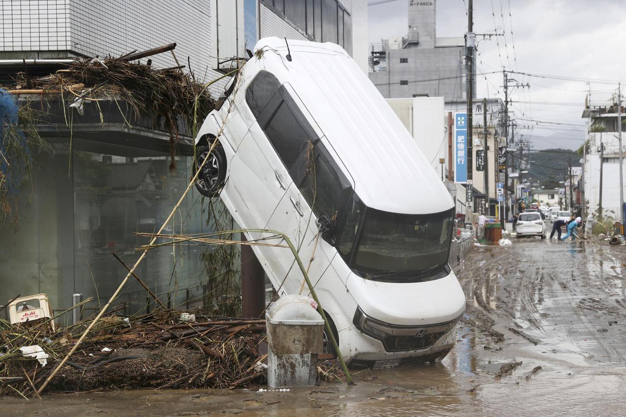 A car is pictured after it was drifted by torrential rain in Hitoyoshi