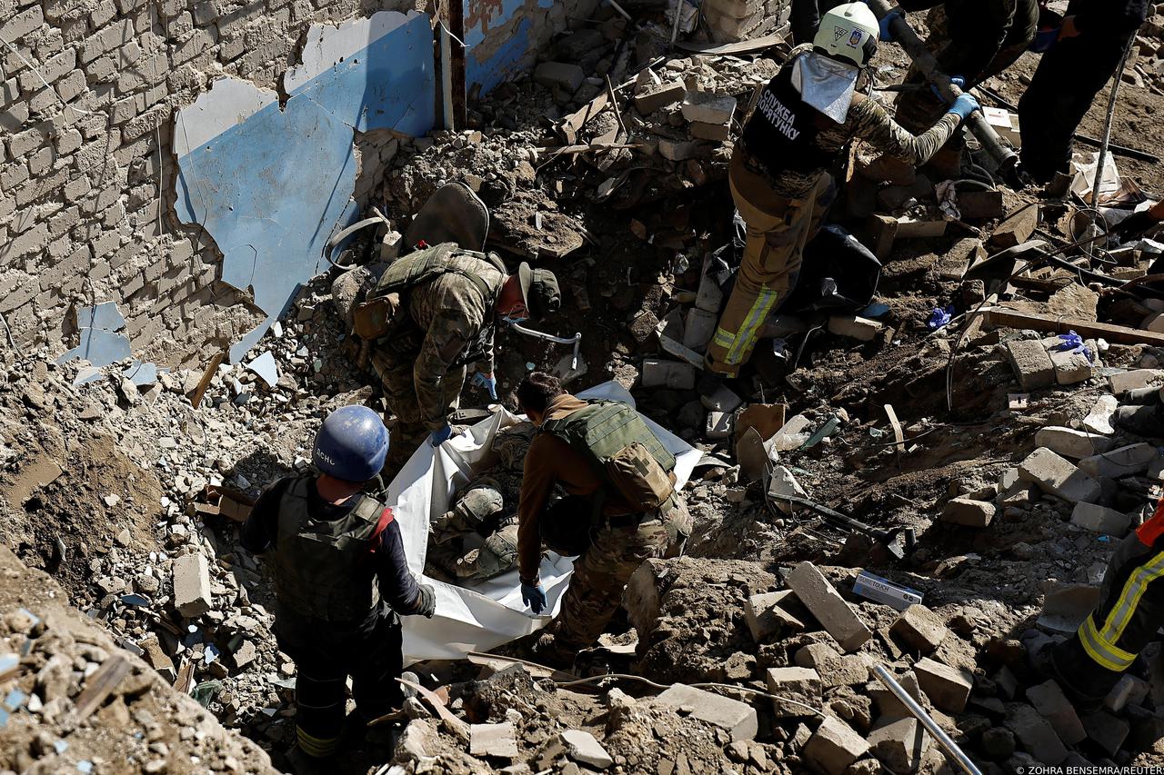 Ukranian army soldiers extract their comrade's body who was found under rubbles in Izium
