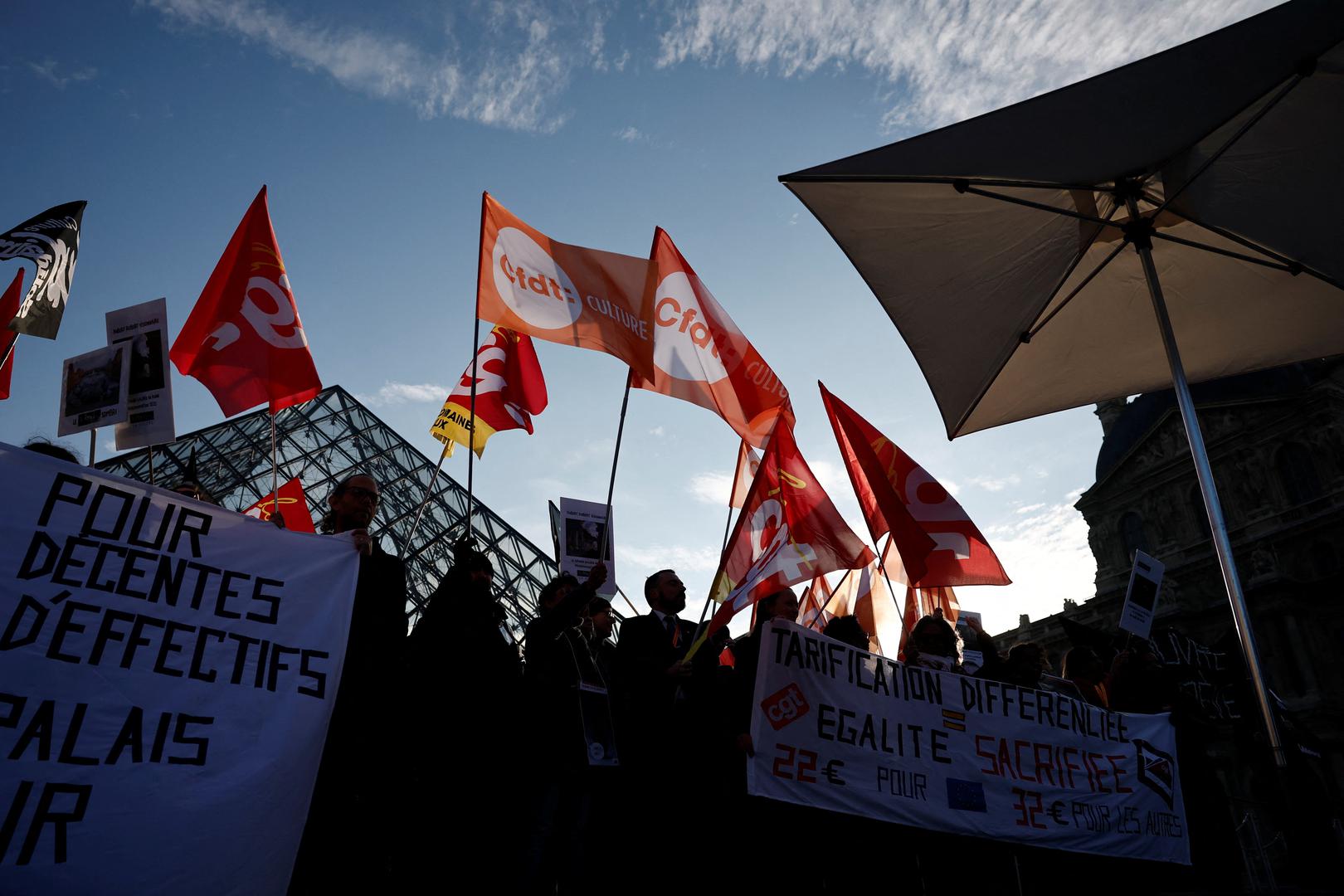 Louvre museum employees on strike hold CGT, CFDT Culture and Sud Solidaires labour unions flags near the glass Pyramid of the closed Louvre museum to protest their working conditions, the state of the museum's buildings and staffing issues, two months after a spectacular heist which saw thieves make off with jewels in broad daylight, in Paris, France, December 15, 2025. REUTERS/Benoit Tessier Photo: BENOIT TESSIER/REUTERS