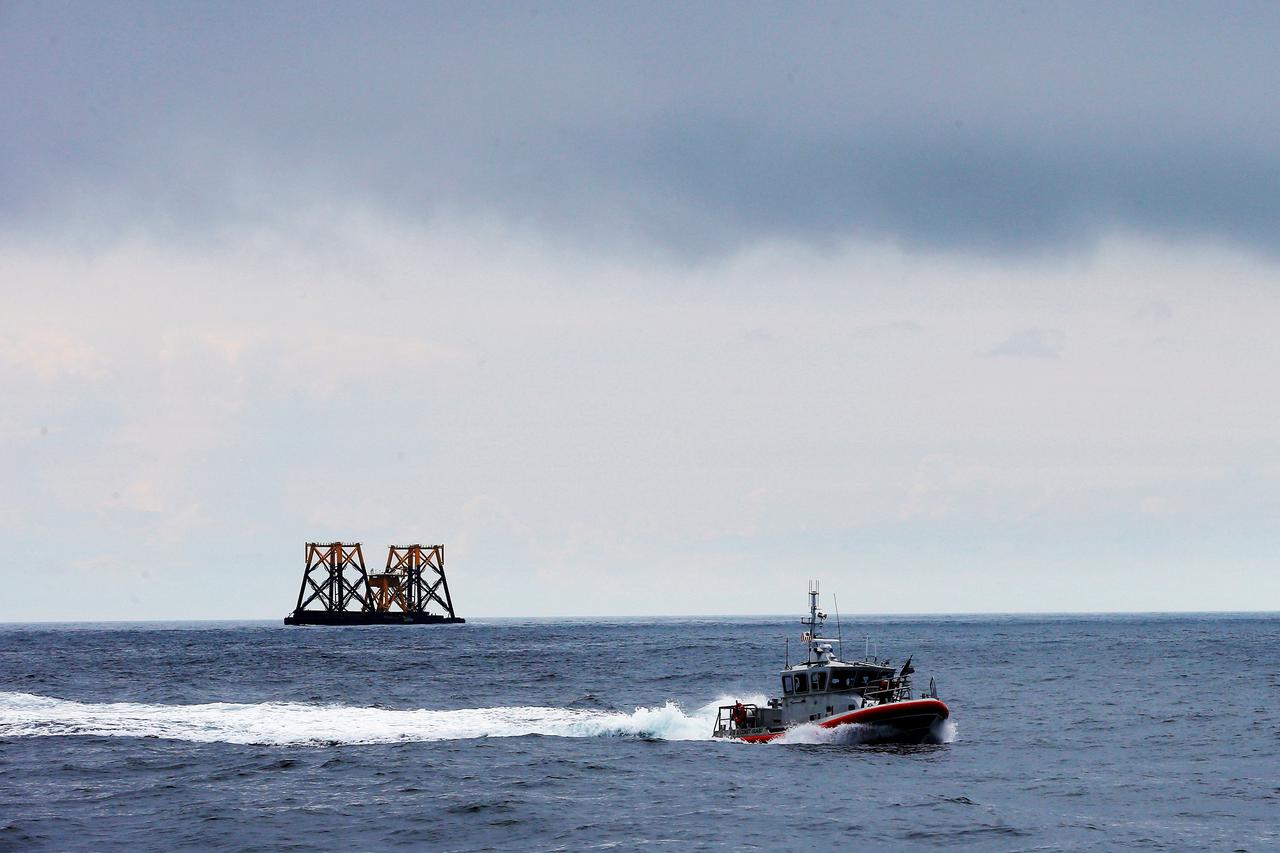 FILE PHOTO: U.S. Coast Guard patrol boat passes a barge carrying support jackets and platforms for wind turbines in the waters of the Atlantic Ocean off Block Island