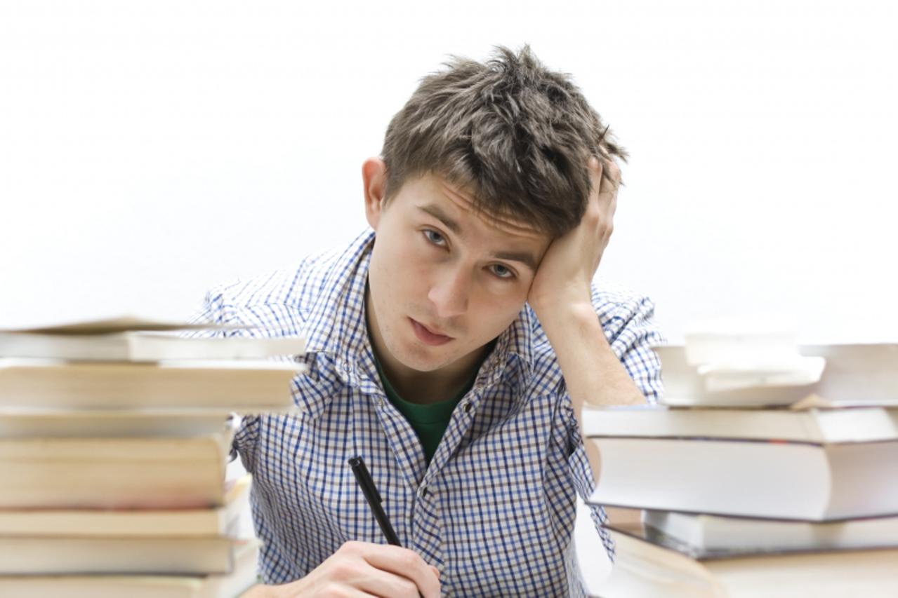 'Young handsome student sitting at a table studying'