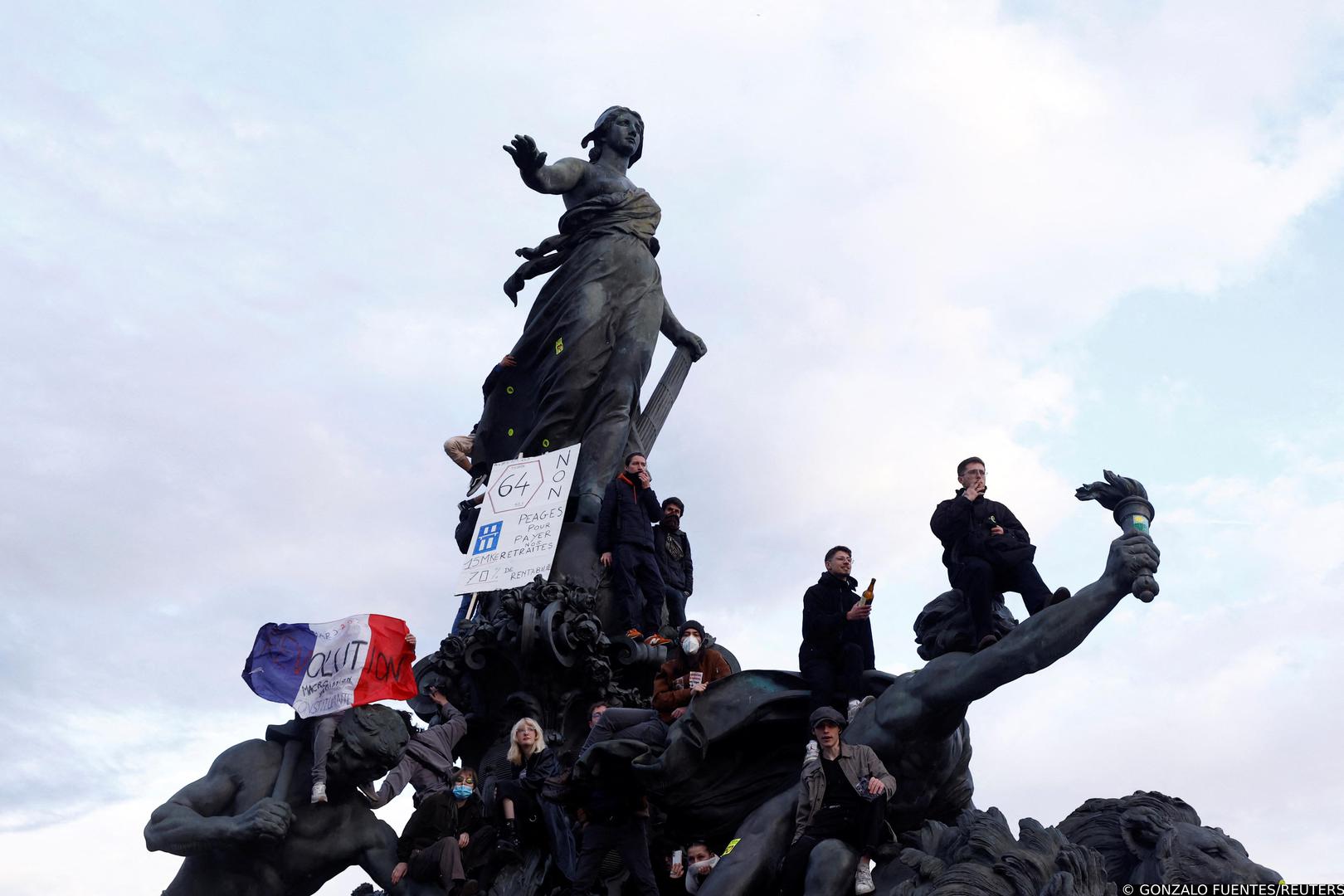 Protesters hold a French national flag as they stand on the statue of the Place de la Nation during a demonstration as part of the tenth day of nationwide strikes and protests against French government's pension reform, in Paris, France, March 28, 2023. REUTERS/Gonzalo Fuentes Photo: GONZALO FUENTES/REUTERS