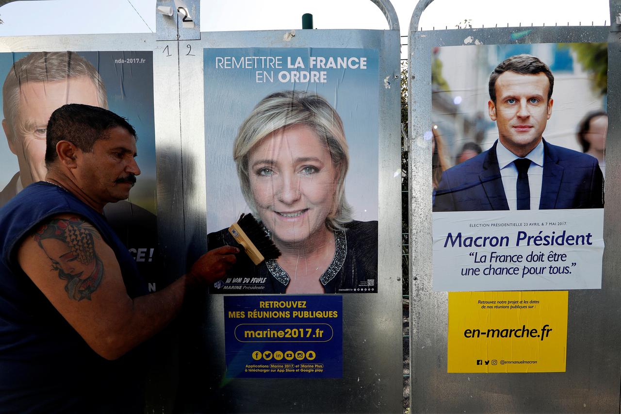 Sauveur, a member of the French National Front (FN) political party pastes a poster on a official billboard for French National Front (FN) political party leader Marine Le Pen as part of the 2017 French presidential election campaign in Antibes Sauveur, a