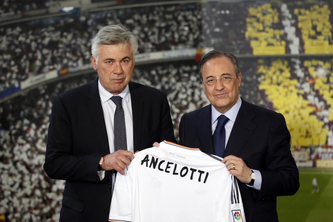 'New Real Madrid coach Carlo Ancelotti (L) holds a Real Madrid jersey as he poses with the club\'s President Florentino Perez during his official presentation at Santiago Bernabeu stadium in Madrid Ju