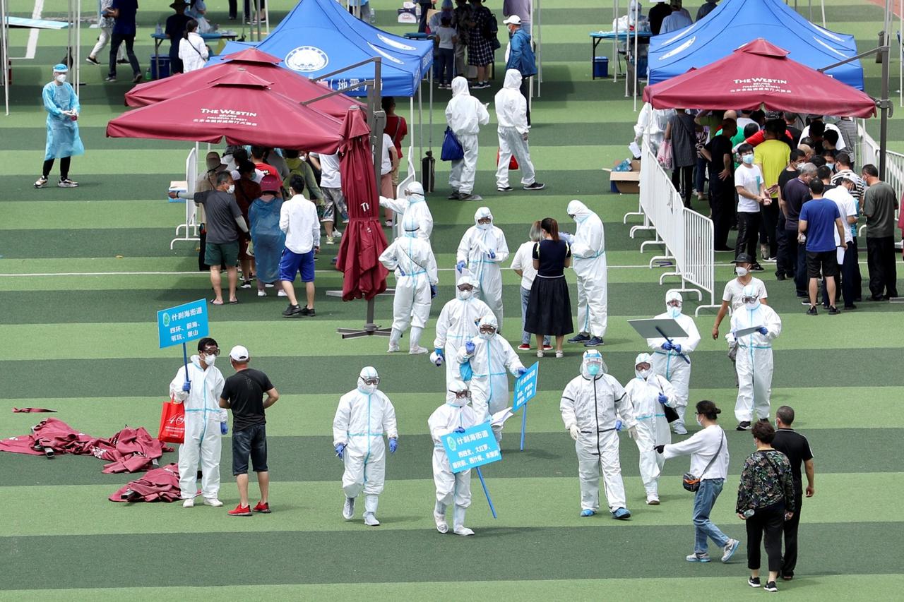 Medical workers help people lining up inside a sports centre for nucleic acid tests in Beijing