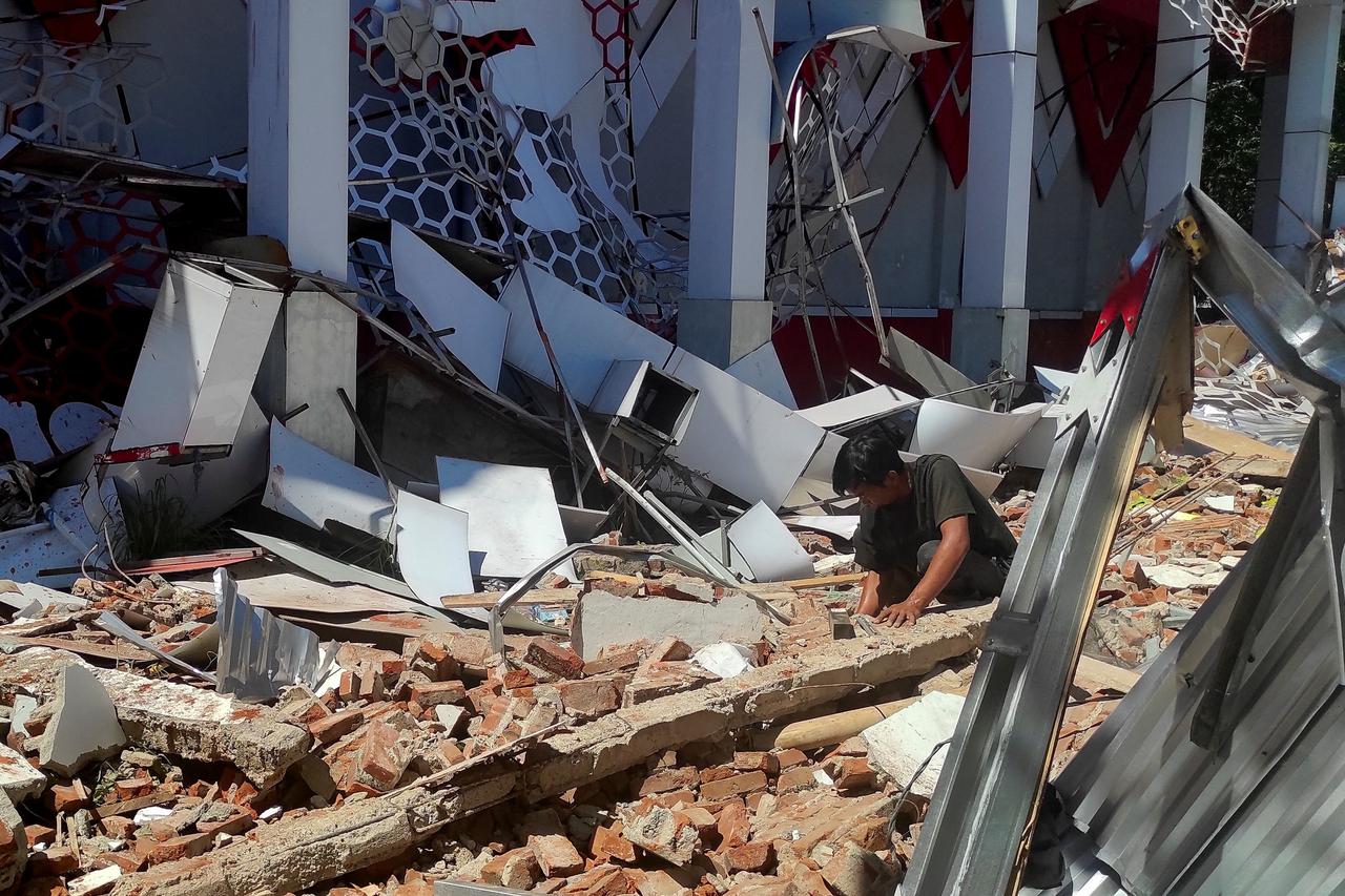 A man inspects debris at the site of a damaged building following an earthquake in Manado