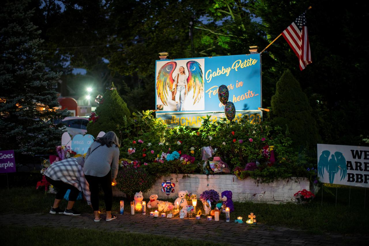 People place candles and flowers during a candlelight vigil for Gabby Petito in Blue Point, New York