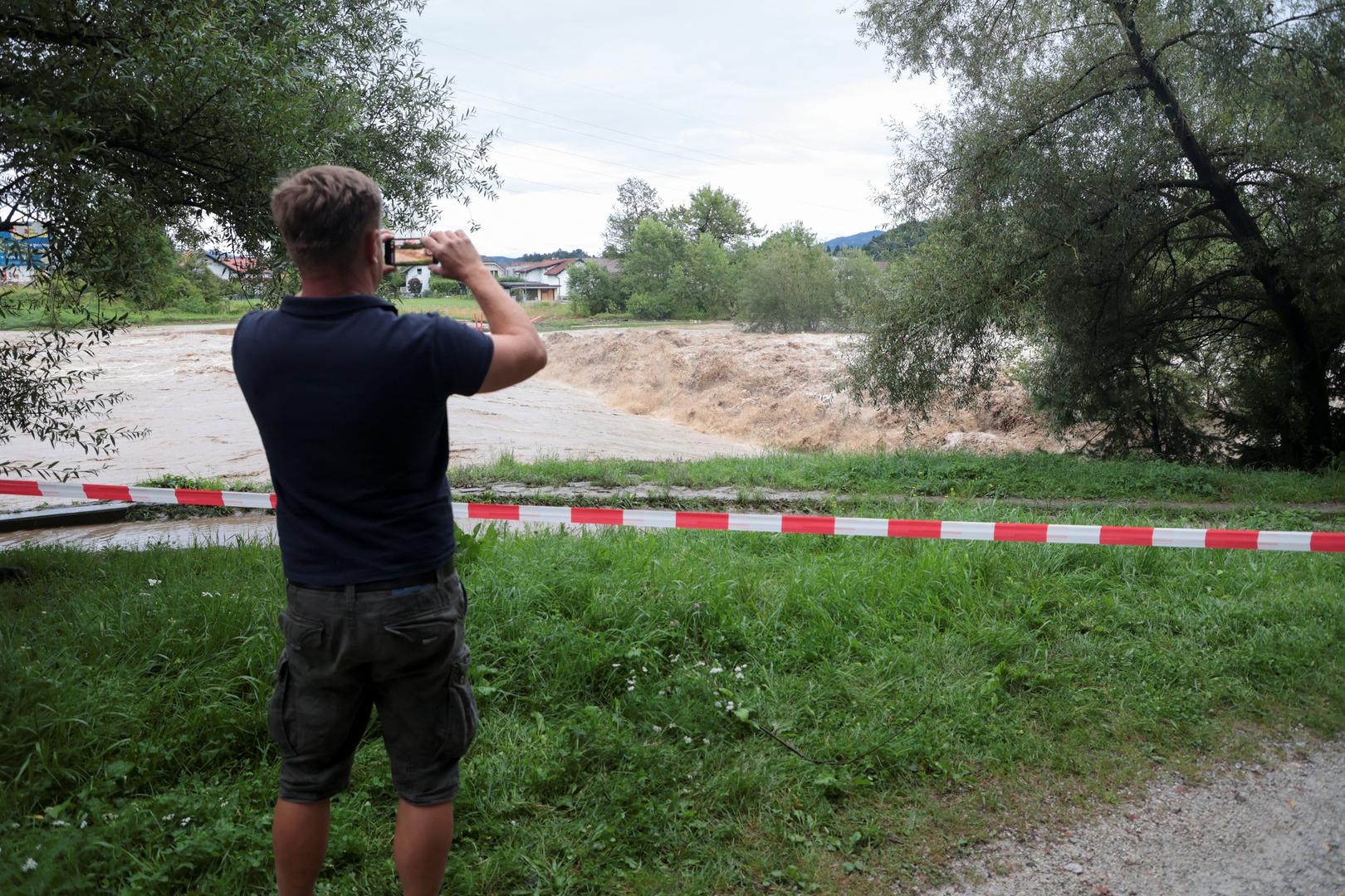 A man uses a smartphone during floods in Domzale, Slovenia August 4, 2023. REUTERS/Borut Zivulovic Photo: BORUT ZIVULOVIC/REUTERS